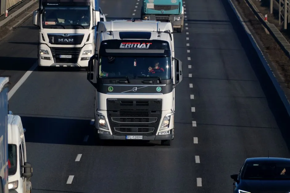 Heavy-duty semi trucks driving on a multi-lane highway, representative of interstate commercial trucking across states
